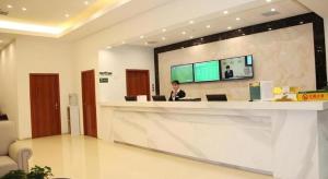 a man sitting at a counter in a lobby at GreenTree Alliance Yichang East Yichang Station Hotel in Yichang