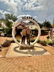 a man and a woman standing in front of a sign at Brian's wild safaris in Fort Portal