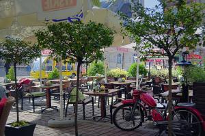 a red motorcycle parked next to tables and trees at Hotel Ester in Kraków