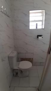 a white bathroom with a toilet and a window at Little Haven Stay in Mzuzu