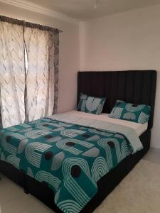 a bedroom with a bed with a green and white comforter at Little Haven Stay in Mzuzu