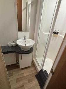 ein Badezimmer mit Waschbecken und Dusche in der Unterkunft Whispering Dunes - Silver Sands Holiday Park in Duffus
