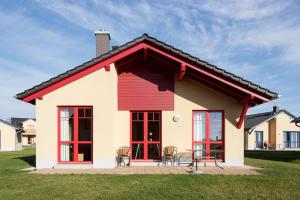 ein Haus mit roten Fenstern sowie einem Tisch und Stühlen in der Unterkunft Holiday home in Markkleeberg near a lake in Markkleeberg