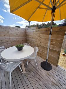 een tafel en stoelen op een houten terras met een parasol bij Puriri Tiny Home in Orewa