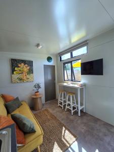 een woonkamer met een gele bank en een tafel bij Puriri Tiny Home in Orewa