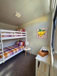 een slaapkamer met twee stapelbedden en een bureau bij Puriri Tiny Home in Orewa +2 foto's