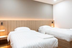 two beds in a hotel room with white sheets at Timber Hotel in Ban Bang Rathuk +3 photos