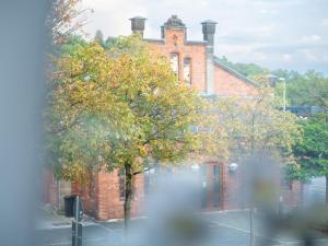 Un edificio de ladrillo con un árbol delante. en GreenTreeHomes - Herzstück Kirsche- im Zentrum Coburgs, en Coburg