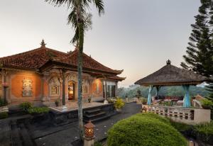 a house with a palm tree in front of it at Villa Air Terjun Bucuan in Sukawati