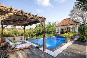 a swimming pool with a pergola next to a house at Villa Air Terjun Bucuan in Sukawati