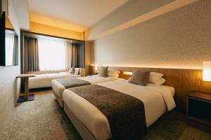 a hotel room with two beds and a couch at Hotel JAL City Sapporo Nakajima Park in Sapporo