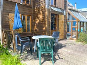 een terras met een tafel, stoelen en een parasol bij Maison avec jardin à TREGASTEL REF 55 in Trégastel