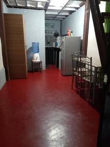 een keuken met een rode vloer met stoelen en een koelkast bij Kubo ni klay in San Isidro