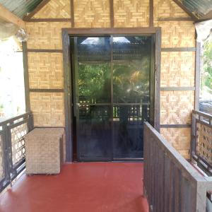 een afgeschermde veranda met een grote glazen deur bij Kubo ni klay in San Isidro