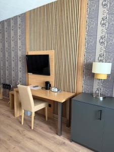 ein Schreibtisch mit Fernseher und Stuhl in einem Zimmer in der Unterkunft Hotel Paffhausen in Wirges