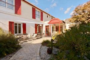 a white house with red shutters and a patio at Villa Kerasy Hotel Spa in Vannes