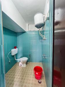 Un baño con inodoro y un cubo rojo. en hotel first view, en Chopta