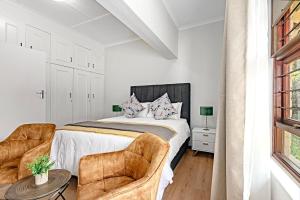 a bedroom with a bed and two chairs at Shai in Johannesburg