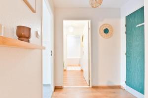 a hallway with white walls and a green door at Candella in Strasbourg