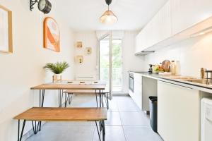 a kitchen with white cabinets and wooden tables at Candella in Strasbourg
