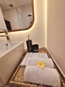 a bathroom with towels and a sink and a mirror at ASAnA Guesthouse in Ubud