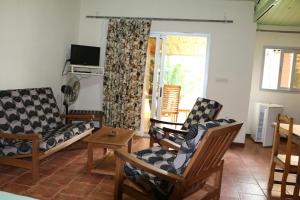 a living room with chairs and a table and a television at Hotel De La Baie in Antsiranana