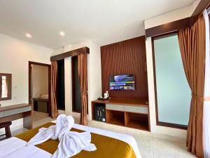 a hotel room with a bed and a tv at ASAnA Guesthouse in Ubud