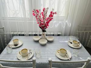 a white table with a vase of pink flowers on it at Каратал 6Б in Taldykorgan