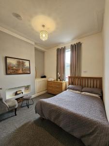 a bedroom with a bed and a chair and a window at Cheerful 4 bedroom close to Uclan, Preston City Center in Preston