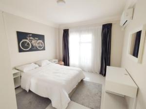 a white bedroom with a bed and a bike on the wall at white Bear in Madinaty