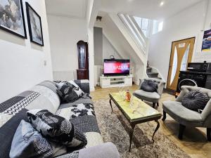 a living room with a couch and a tv at Cheerful 4 bedroom close to Uclan, Preston City Center in Preston
