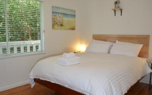 ein Schlafzimmer mit einem weißen Bett mit Handtüchern darauf in der Unterkunft Classic Meets Contemporary 1960's Beach House in Malua Bay