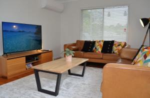 ein Wohnzimmer mit einer Couch und einem Couchtisch in der Unterkunft Classic Meets Contemporary 1960's Beach House in Malua Bay