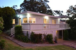 ein kleines weißes Haus mit einer großen Terrasse in der Unterkunft Classic Meets Contemporary 1960's Beach House in Malua Bay