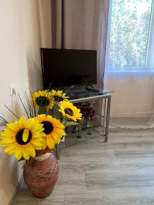 a vase filled with yellow flowers in a living room at Sigulda's Laimas Apartment Self-Check in in Sigulda