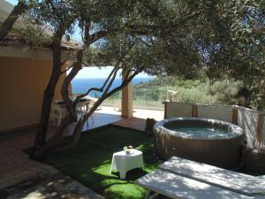 a backyard with a tree and a hot tub at Torre Comfort House in Torre delle Stelle