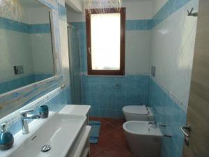a blue tiled bathroom with a sink and a toilet at Torre Comfort House in Torre delle Stelle
