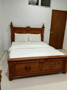 a wooden bed with white sheets in a room at Hotel Nusantara in Jertih +1 photo
