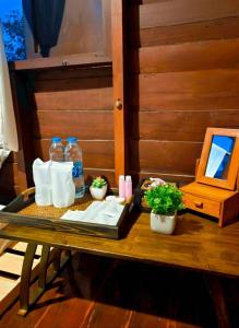 a table with bottles of water and napkins and plants at BaanBaimai Homestay in Chiang Rai