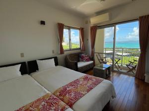 a bedroom with two beds and a view of the ocean at シーブリーズ古宇利 in Nakijin