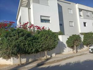 a white building with trees in front of a building at New Sweet Home Soukra in Sukrah