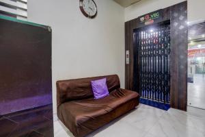 una silla de cuero marrón en una habitación con reloj en Collection O Bank More Dhanbad Formerly Hotel Sri Ganesh Ji, en Dhanbād