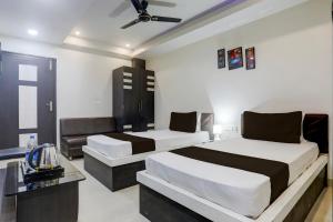 una habitación de hotel con dos camas y un sofá en Collection O Bank More Dhanbad Formerly Hotel Sri Ganesh Ji, en Dhanbād