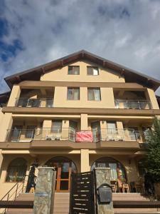 a tan building with a sign in front of it at Pensiunea Alex in Cheia