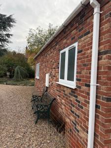 MartonにあるBright, Stylish 1 KS Bed Bungalow with Private Gardenの窓のあるレンガの壁沿いに2つのベンチがある