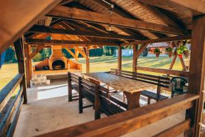 a wooden table and benches in a pavilion with a fireplace at Bükkfői vendégház in Borzont