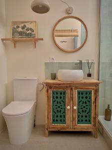 a bathroom with a sink and a toilet and a mirror at Studio Ker Boucan à 5 min de la plage in Saint-Paul