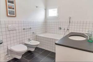 een witte badkamer met een toilet en een wastafel bij Chesa Saura in Ponte +29 foto's