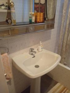 een witte wastafel in een badkamer met een spiegel bij Habitación de matrimonio in Madrid