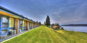 a house with a lawn next to a body of water at Lake Jindabyne Hotel in Jindabyne